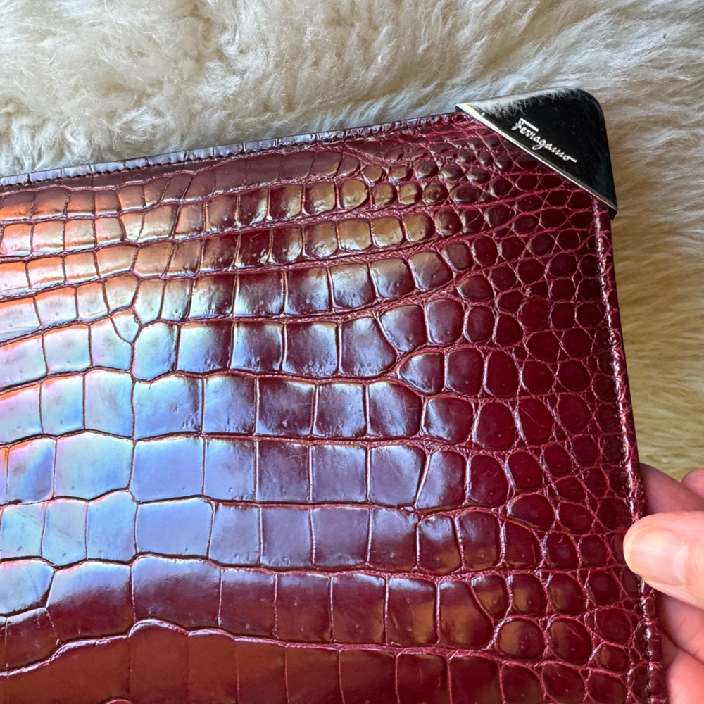 Ferragamo clutch bag in burgundy leather with silver corner detail.